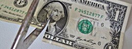 scissors cutting a one dollar bill