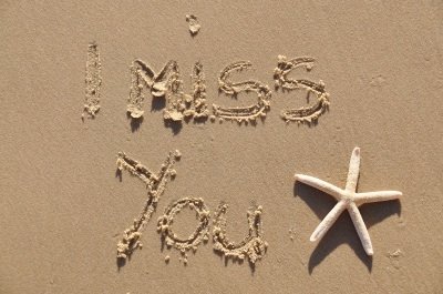 The words "I miss you" written in sand